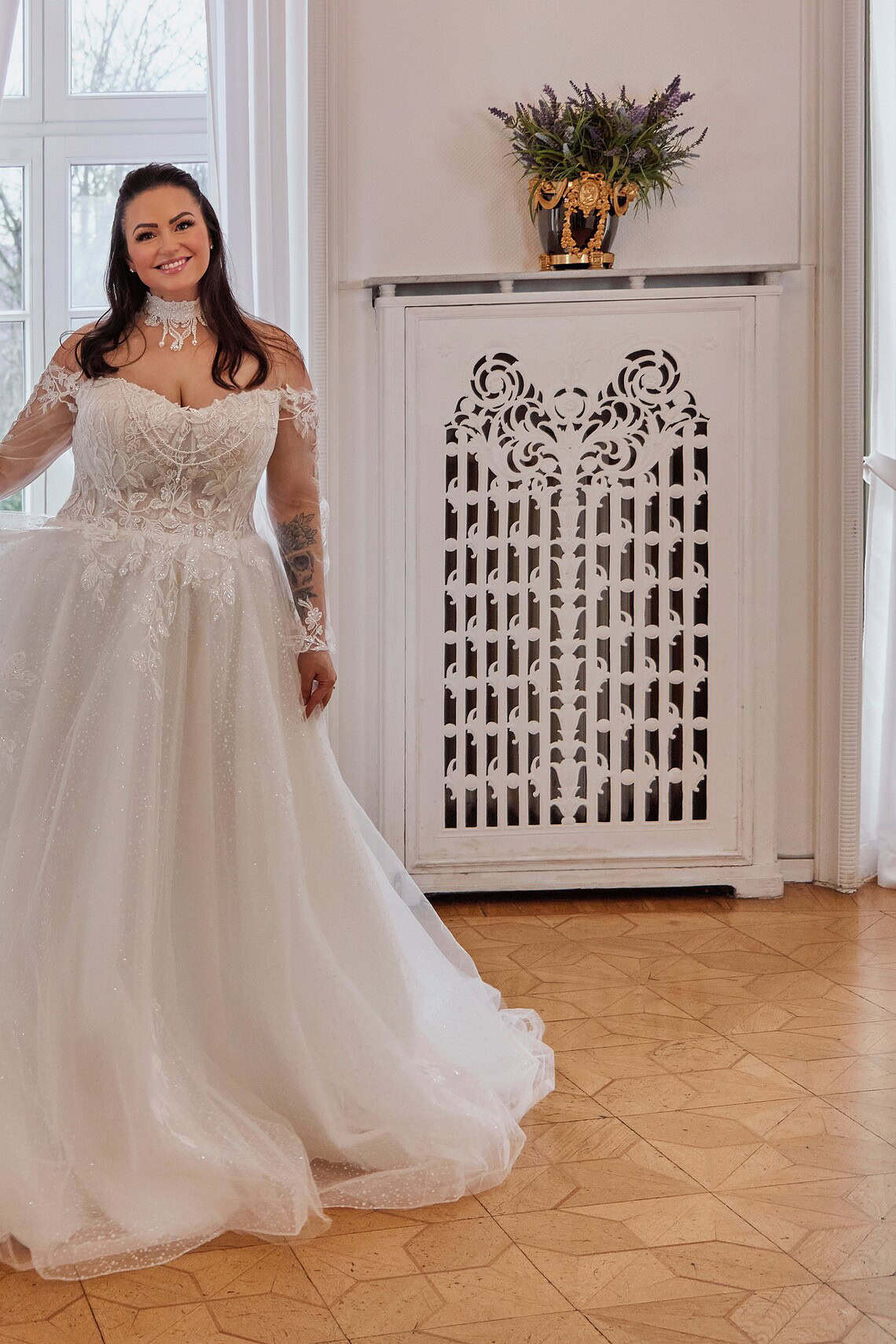 Braut in eleganter Hochzeitskleidung im festlichen Raum mit weißen Vorhängen.
