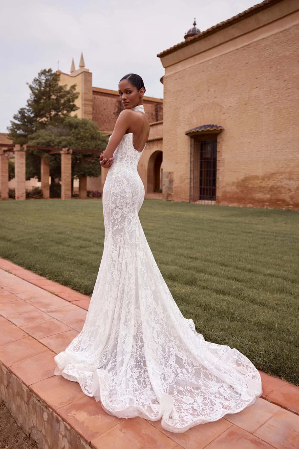 Elegantes Brautkleid mit Spitze und Schleppe vor historischer Kulisse.